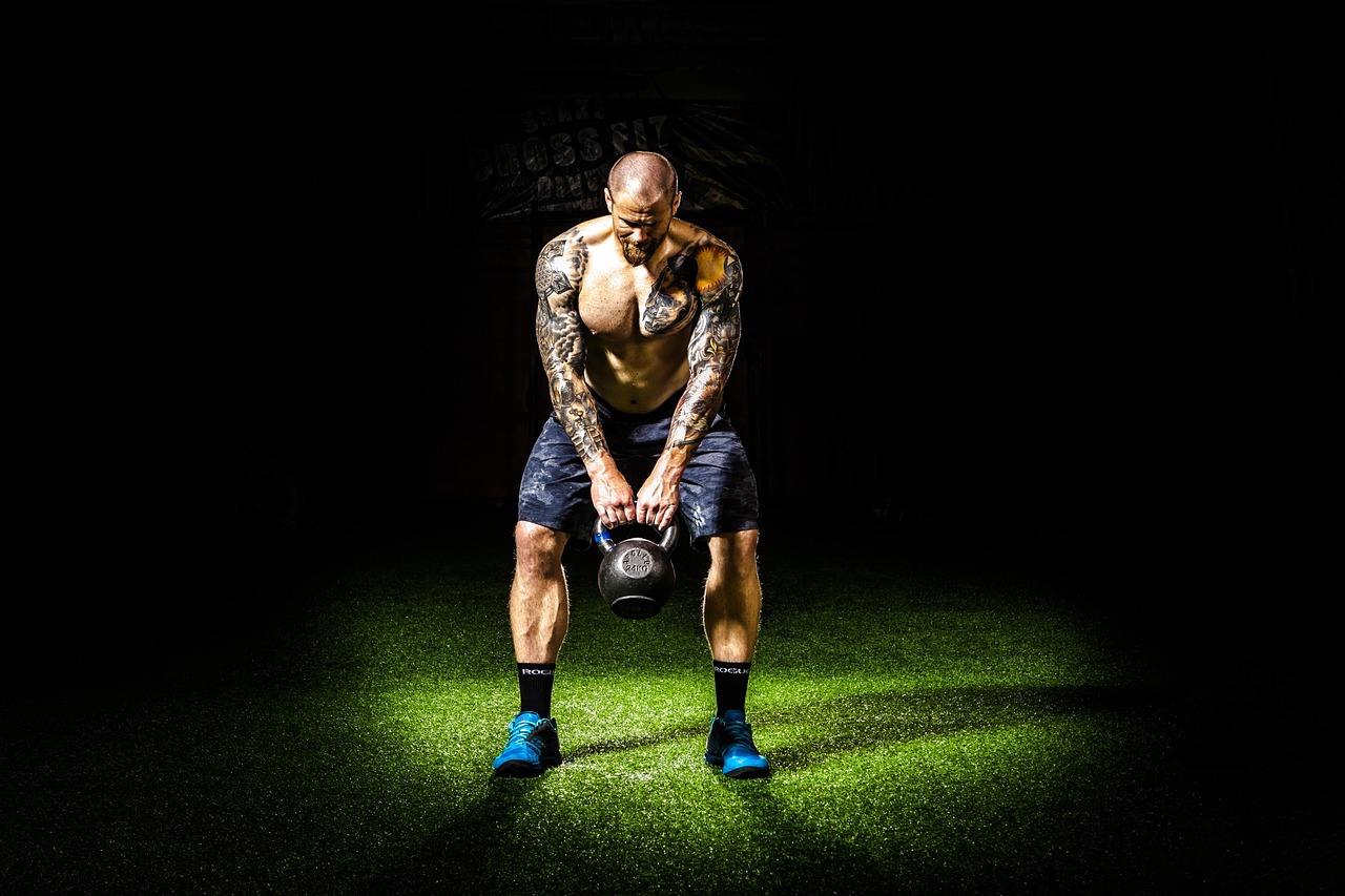A kettlebell swing in a single spotlight on a dark floor
