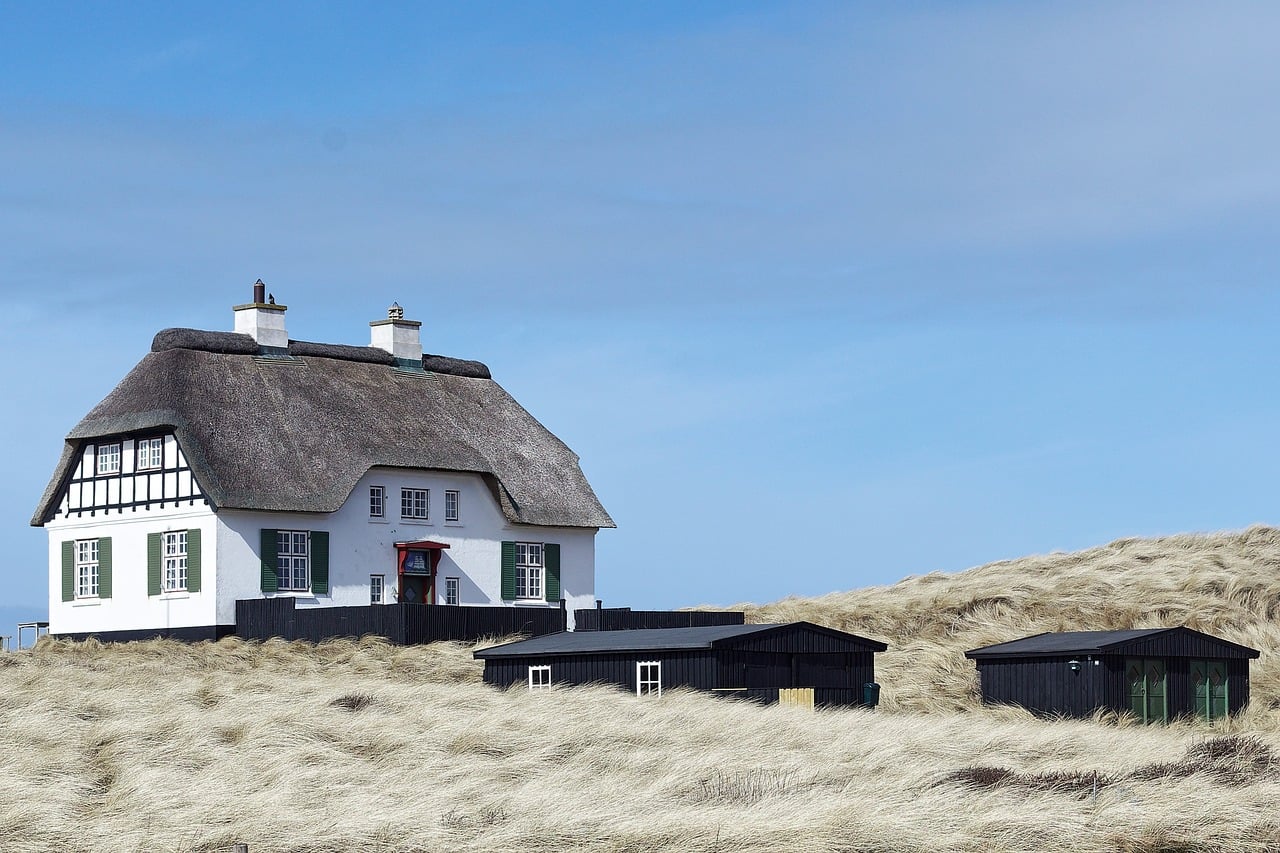 A white thatched house standing alone in pale dune grass